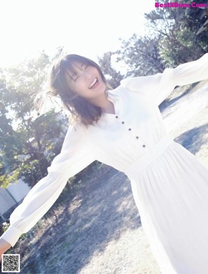 A woman in a white dress standing in a field.