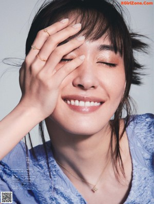 A woman in a gray sweater is posing for a magazine.