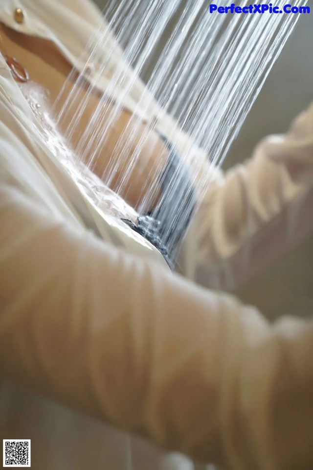 A woman in a white shirt is washing her hands.