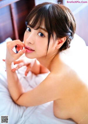 A naked woman laying on a bed with white sheets.