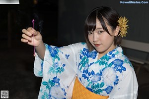 A woman in a blue and white kimono sitting on a bench.