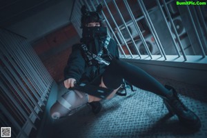 A woman wearing a mask and holding a gun on top of a building.