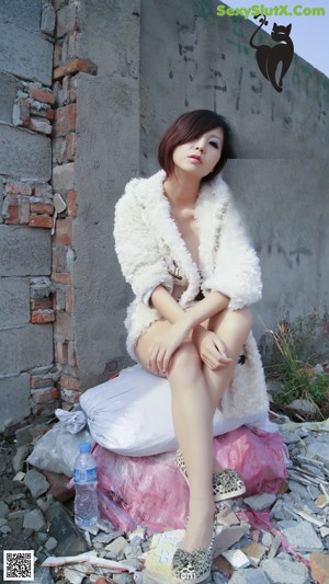 A woman in a white fur coat posing for the camera.