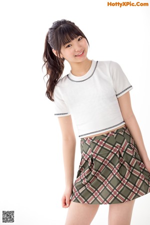 A woman in a white shirt and plaid skirt crouching on the floor.