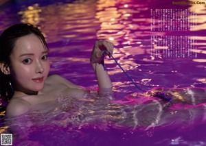 A woman in a pool holding a cell phone in her hand.