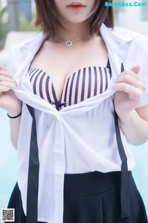 A woman in a white shirt and black skirt is standing on a balcony.