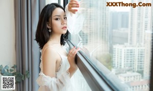A woman sitting on a yellow chair in a white dress.