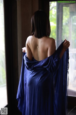 A woman in a blue dress is holding a blue scarf.