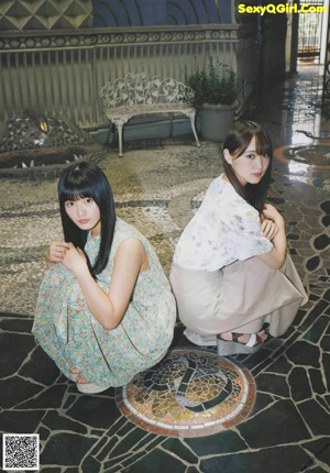 A couple of young women sitting on a swing.