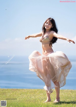 A woman in a bikini sitting on a grassy field.