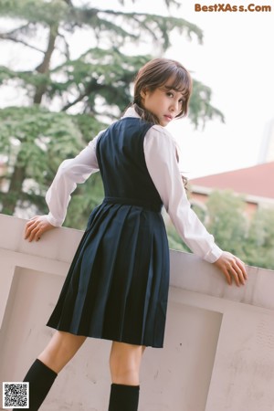 A woman in a school uniform holding a stick.