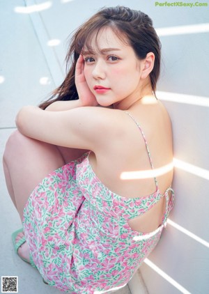 A woman in a pink shirt and blue panties posing for a picture.