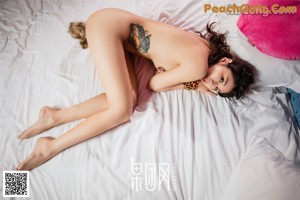 A woman in a pink and black lingerie sitting on a bed.