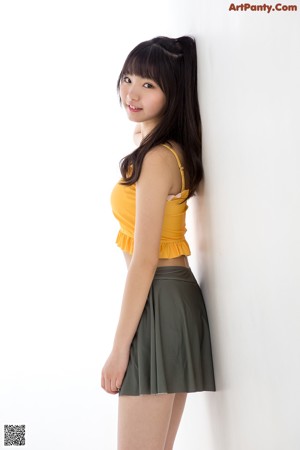 A woman in a yellow top and a green skirt.